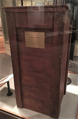 Affixed to the front of the pulpit is a small plaque that reads "Vancouver Avenue First Baptist Church First Pulpit Handcrafted by Rev. Dr. O.B. Williams from Apple Crates in 1945".